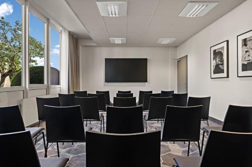a conference room with chairs and a projection screen at Leonardo Hotel Mainz in Mainz