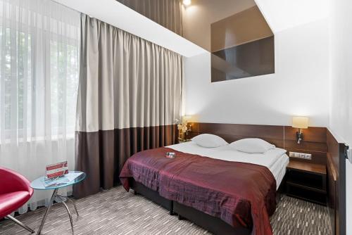 a hotel room with a bed and a red chair at Park Hotel Diament Zabrze - Gliwice in Zabrze
