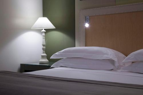 a bed with white pillows and a table with a lamp at Starhotels Tuscany in Florence