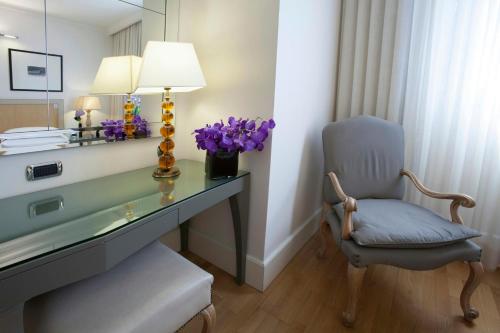 a desk with a chair and a lamp and purple flowers at Starhotels Tuscany in Florence