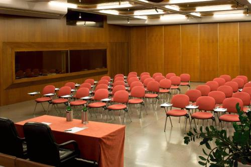 a conference room with red chairs and tables and a screen at Starhotels Cristallo Palace in Bergamo