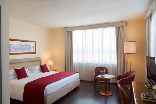 a hotel room with a bed and a table and a window at Starhotels Business Palace in Milan