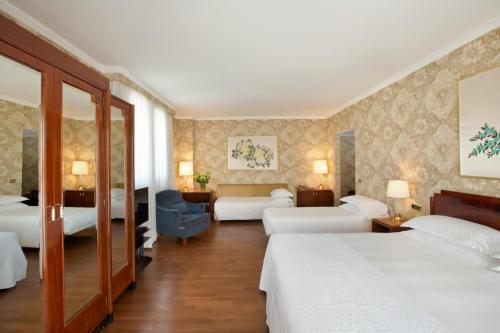 a hotel room with two beds and a chair at Starhotels Du Parc in Parma