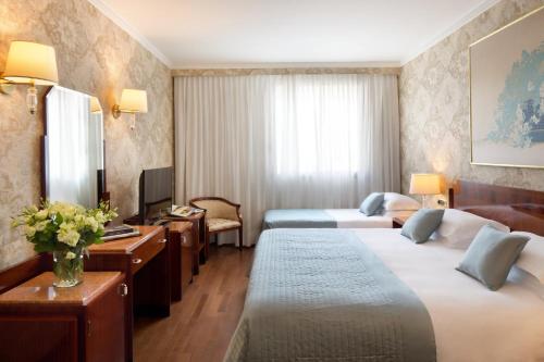 a hotel room with two beds and a desk at Starhotels Du Parc in Parma