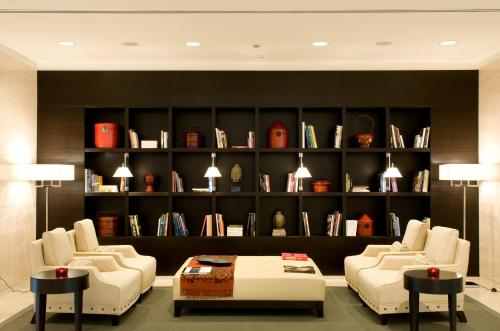 a living room with two chairs and a book shelf at Starhotels Grand Milan in Saronno
