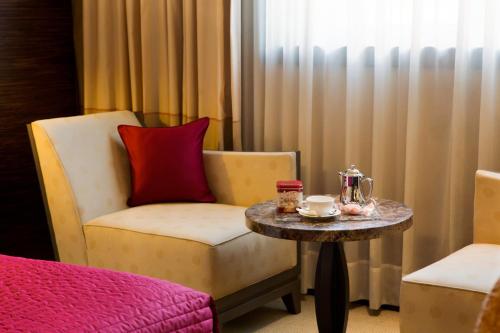 a room with a chair and a table with a coffeeucer at Starhotels Grand Milan in Saronno