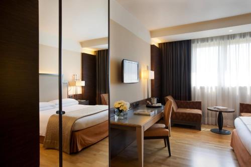 a hotel room with a bed and a desk at Starhotels Grand Milan in Saronno