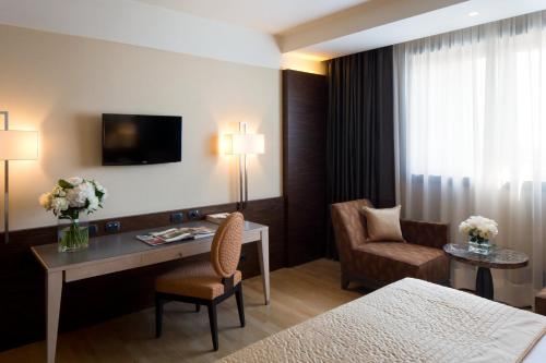 a hotel room with a desk and a bed at Starhotels Grand Milan in Saronno