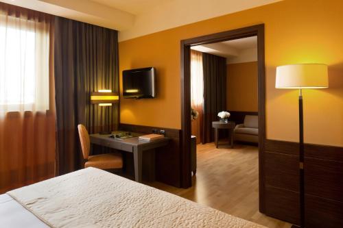 a hotel room with a bed and a desk and a television at Starhotels Grand Milan in Saronno
