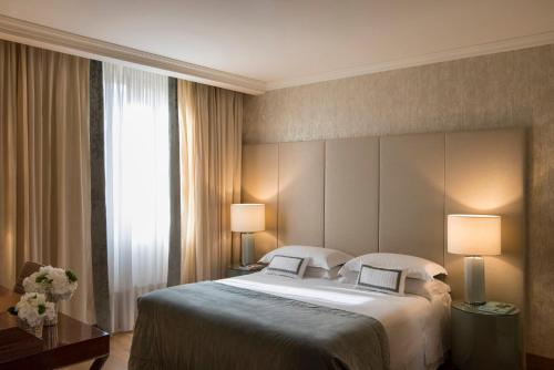 a bedroom with a large bed with two lamps at Rosa Grand Milano - Starhotels Collezione in Milan