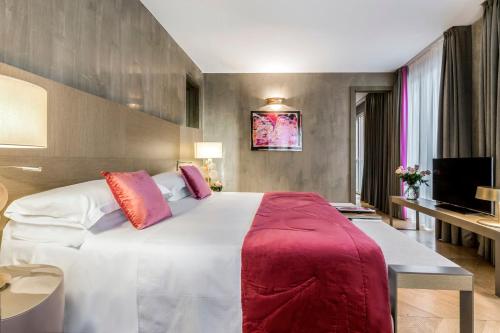 a bedroom with a large white bed with red pillows at Rosa Grand Milano - Starhotels Collezione in Milan