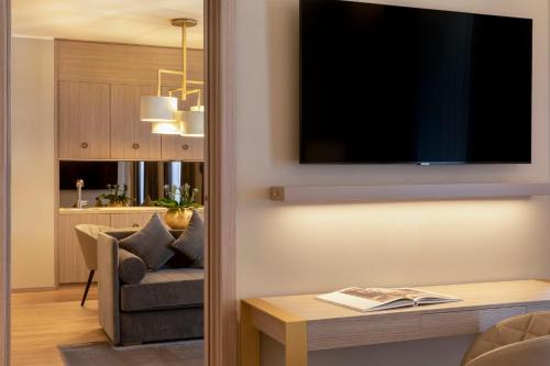 a living room with a chair and a television on a wall at Rosa Grand Milano - Starhotels Collezione in Milan