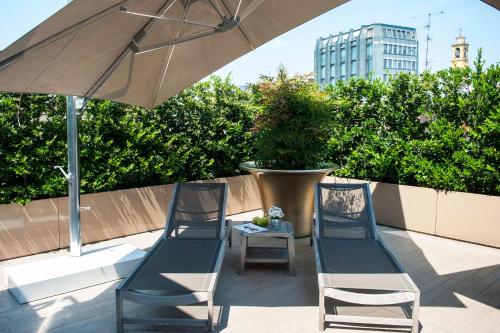 two chairs and a table under an umbrella on a patio at Rosa Grand Milano - Starhotels Collezione in Milan