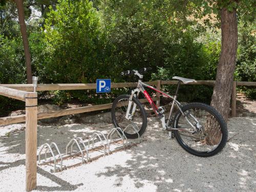 a bike parked next to a fence with a parking sign at Les Sables d'Ocre & SPA in Roussillon