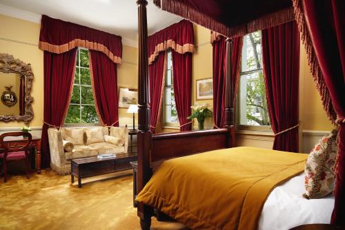 a bedroom with a bed and a couch and windows at The Gore London - Starhotels Collezione in London