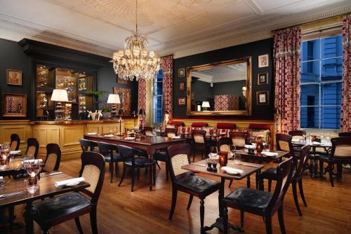 a restaurant with wooden tables and chairs and a chandelier at The Gore London - Starhotels Collezione in London