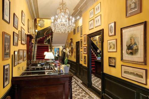 a hallway with yellow walls and a chandelier at The Gore London - Starhotels Collezione in London