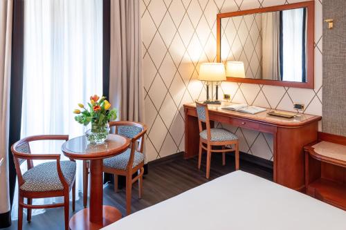 a hotel room with a desk and a table with chairs at Starhotels Majestic in Turin