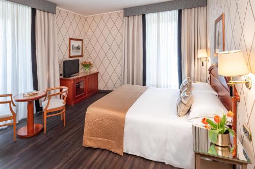 a hotel room with a bed and a table and a tv at Starhotels Majestic in Turin