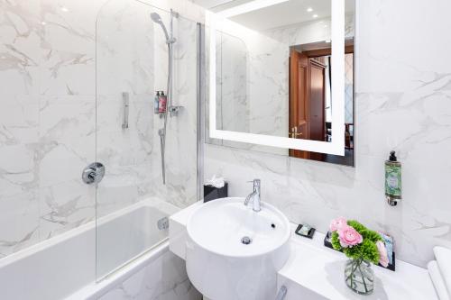 a white bathroom with a sink and a bath tub at Starhotels Majestic in Turin