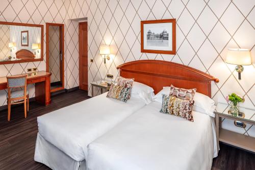 a bedroom with a large white bed and a desk at Starhotels Majestic in Turin