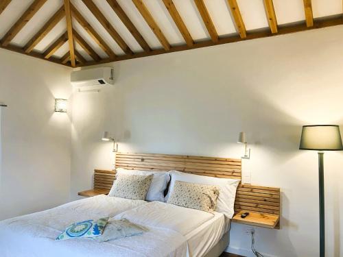 a bedroom with a white bed with a wooden headboard at Casa MARGO in Lajes