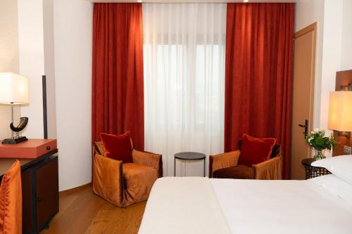 a hotel room with a bed and two chairs at Starhotels Michelangelo Florence in Florence