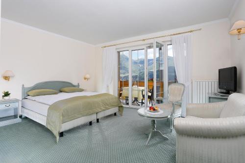 a bedroom with a bed and a couch and a chair at Landhaus Hotel Kristall in Marlengo