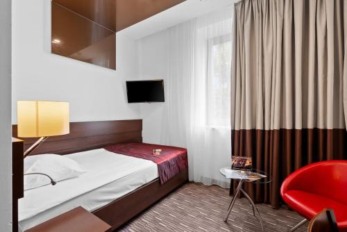 a hotel room with a bed and a red chair at Park Hotel Diament Zabrze - Gliwice in Zabrze