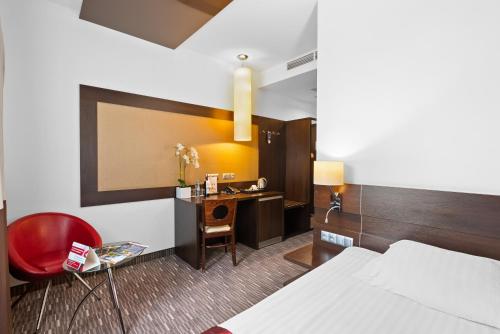 a hotel room with a bedroom with a desk and a bed at Park Hotel Diament Zabrze - Gliwice in Zabrze