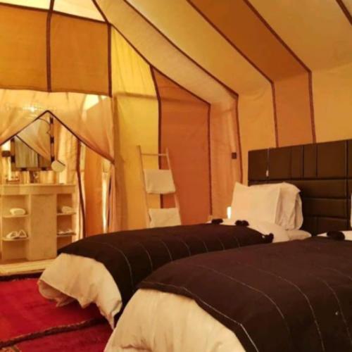 a bedroom with two beds in a tent at Merzouga tente luxury in Merzouga