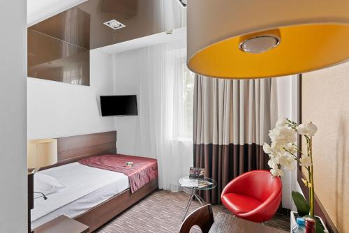 a hotel room with a bed and a red chair at Park Hotel Diament Zabrze - Gliwice in Zabrze