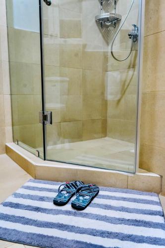 two pairs of flip flops sitting on a rug in a shower at Cozy Luxe Haven Lakeside Condo in Entebbe in Entebbe