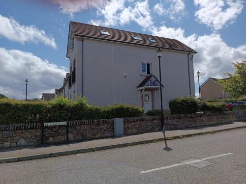ein weißes Gebäude am Straßenrand in der Unterkunft Woodgrove Holiday Homes in Inshes