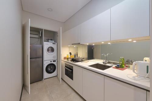 a kitchen with white cabinets and a washer and dryer at Sky Suites KLCC - Luxury Service Apartments Near Petronas Twin Tower in Kuala Lumpur