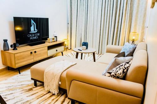 a living room with a couch and a flat screen tv at Cozy Luxe Haven Lakeside Condo in Entebbe in Entebbe
