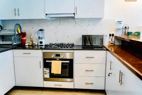 a kitchen with white cabinets and a stove top oven at Cozy Luxe Haven Lakeside Condo in Entebbe in Entebbe