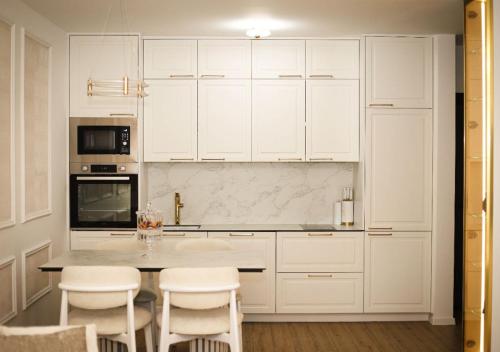 a kitchen with white cabinets and a table and chairs at Modern Apartment Peje in Peje