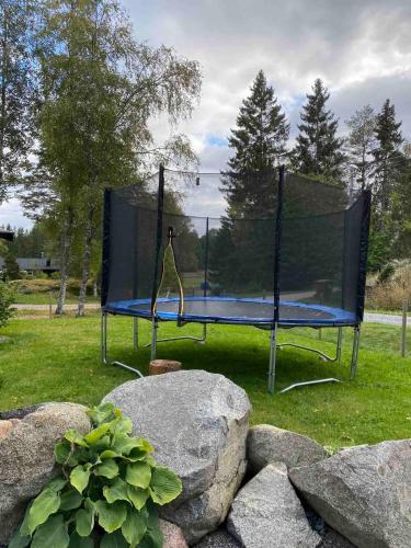 a trampoline in a park with rocks in the grass at Cheerful house with sauna and bathtub in Almunge