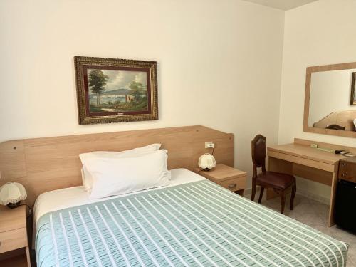 a bedroom with a bed and a desk and a mirror at Albergo Edera in Salsomaggiore Terme