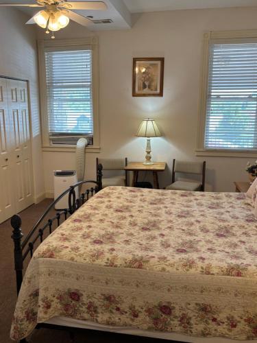 a bedroom with a bed and a table and two windows at Hermann Crown Suites in Hermann
