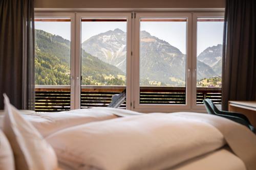 a bedroom with a bed and a window with mountains at Hotel Birkenhöhe in Hirschegg