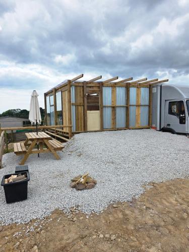 a building with a picnic table and a trailer at Miss Francis Horse Wagon in Looe