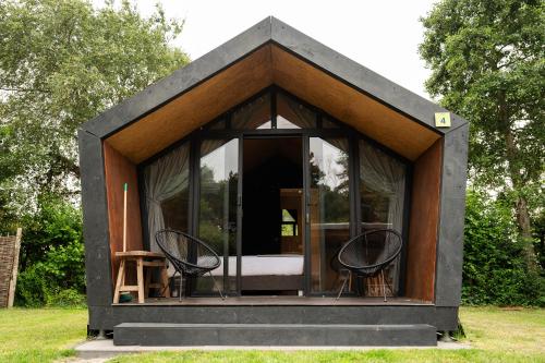 a tiny house with two chairs in the grass at Tenthuisje in het groen, een suite met eigen badkamer in Callantsoog