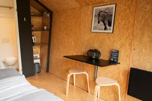 a room with a bed and a table and two stools at Tenthuisje in het groen, een suite met eigen badkamer in Callantsoog