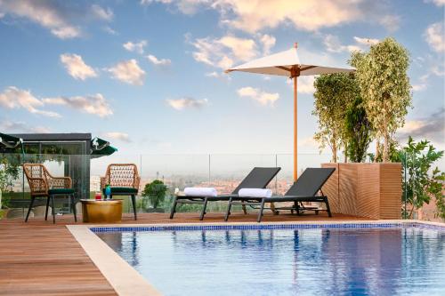 a pool with chairs and an umbrella on a building at NearYo Hotels in Marrakech