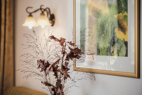a vase with a plant in front of a painting at Biohotel Rastbichlhof in Neustift im Stubaital