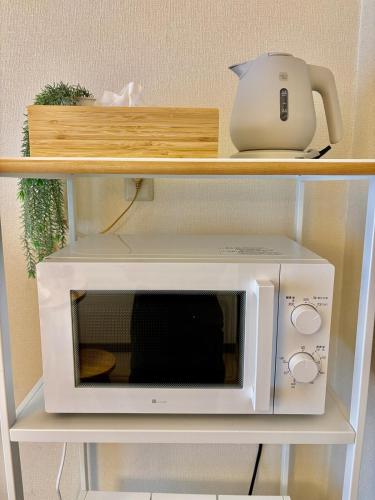 a microwave on a shelf with a tea pot on it at Hachioji House 206 Apartment in Hachioji