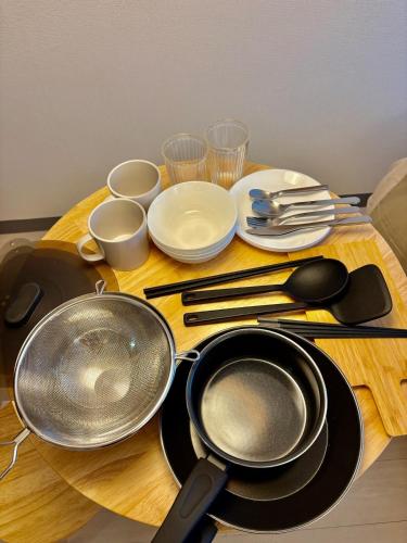 a wooden table with utensils and plates and frying pans at Hachioji House 206 Apartment in Hachioji