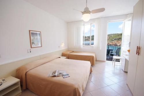 a hotel room with two beds and a balcony at Hotel Dino in Capoliveri